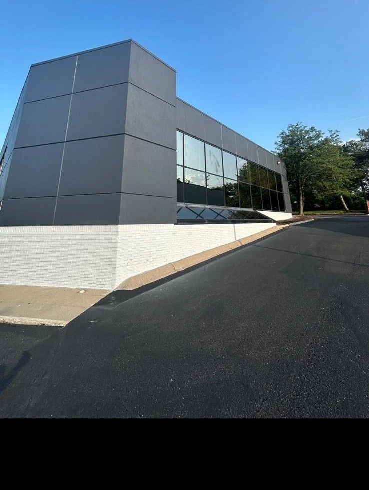 The same building after Gashi Painting repaint, modern grey panels with white brick base