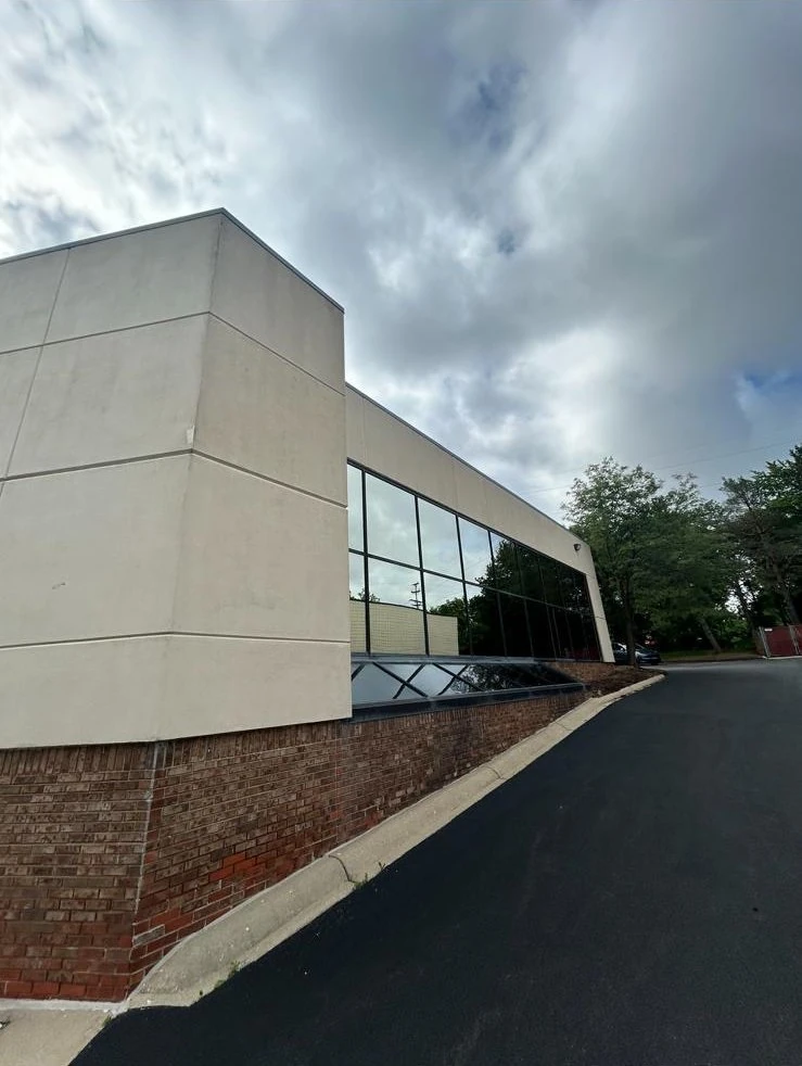 Commercial building exterior before, faded beige panels with red brick base