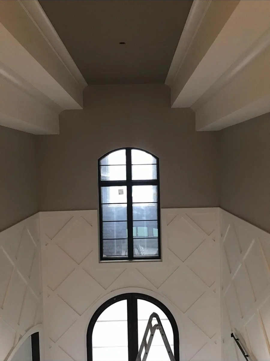 Two-story foyer with white diamond-pattern wainscoting and taupe walls