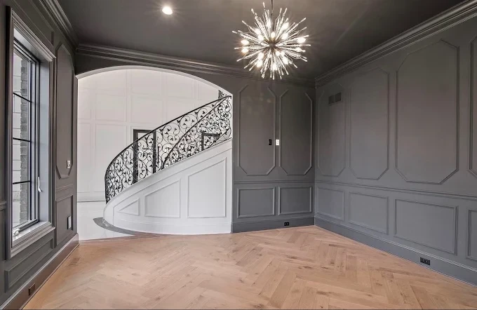 Gray paneled room with a curved staircase and starburst chandelier, painted by Gashi Painting